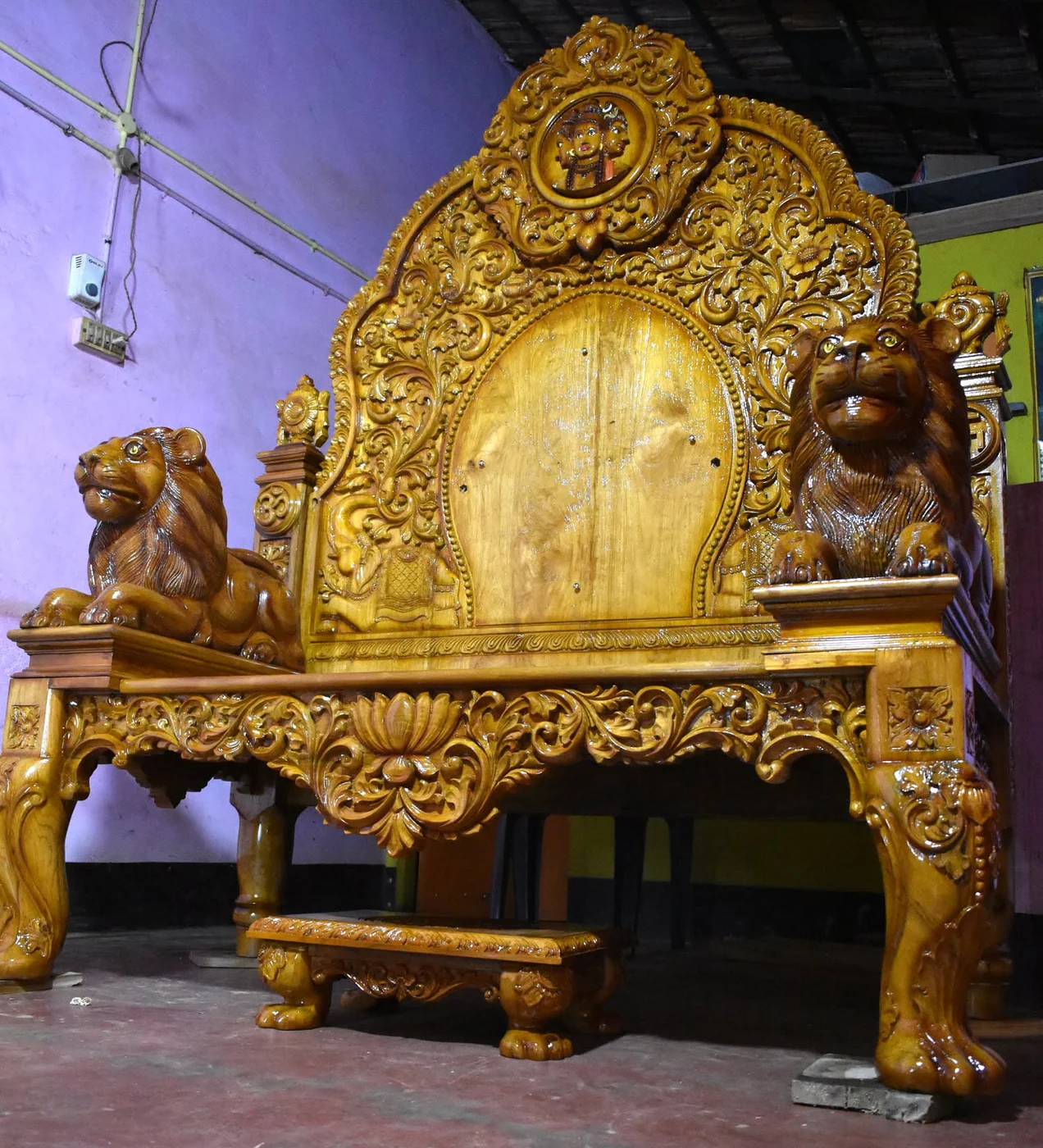 Carved simhasana with tiered crown, pillars and floral relief panels