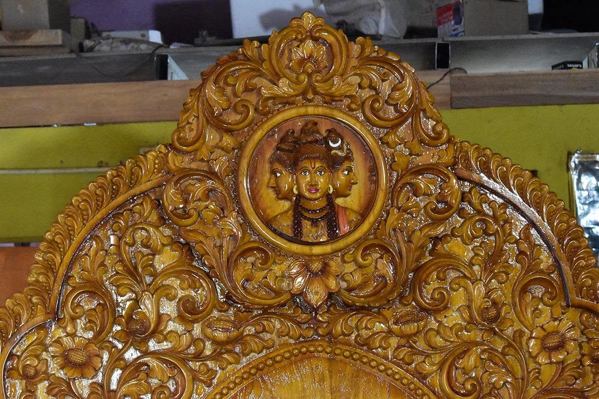 Detail of simhasana carving showing the crest and side scrollwork — piece 09 of the collection